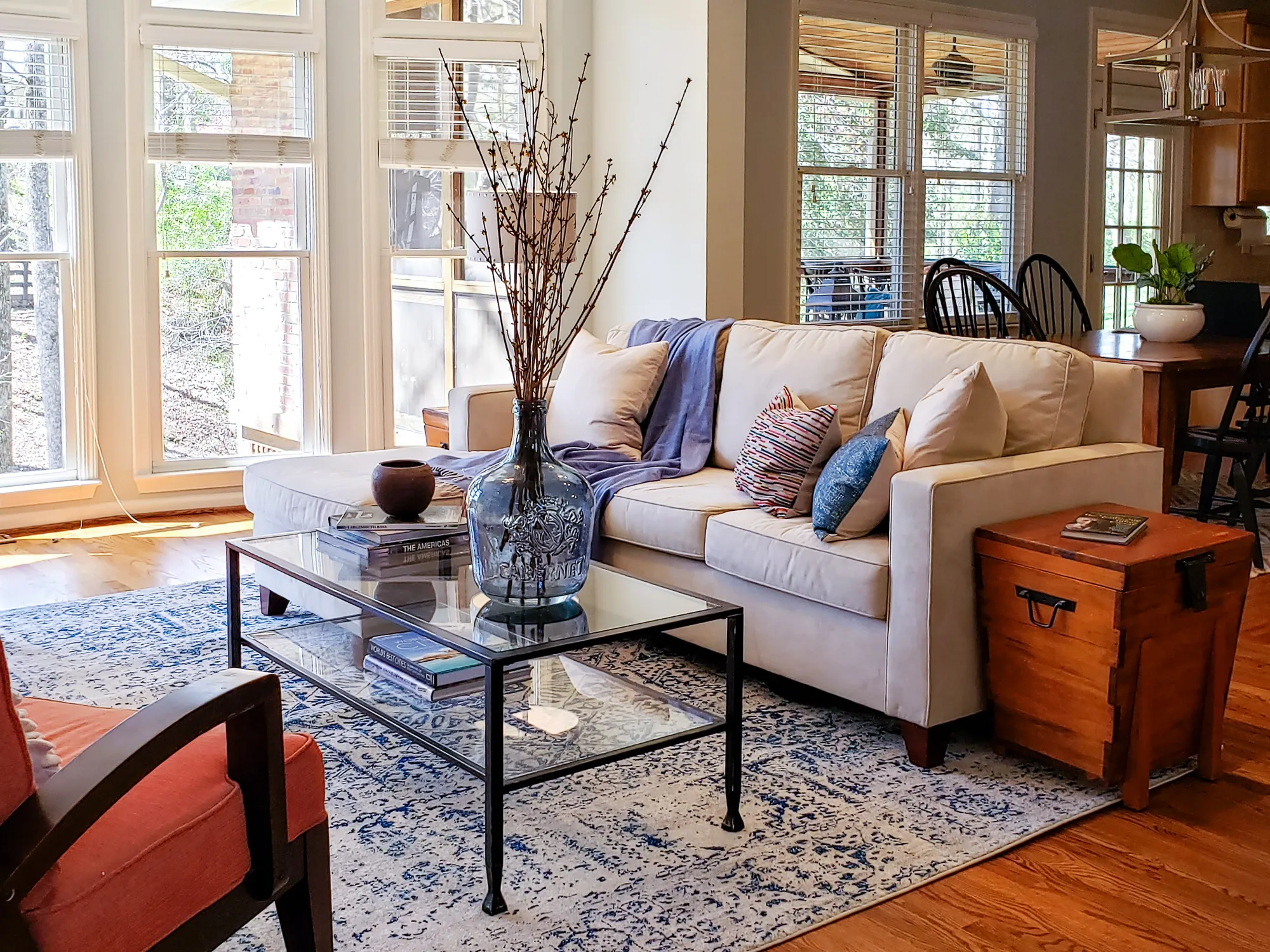 A cream sofa and glass coffee table in front of tall windows