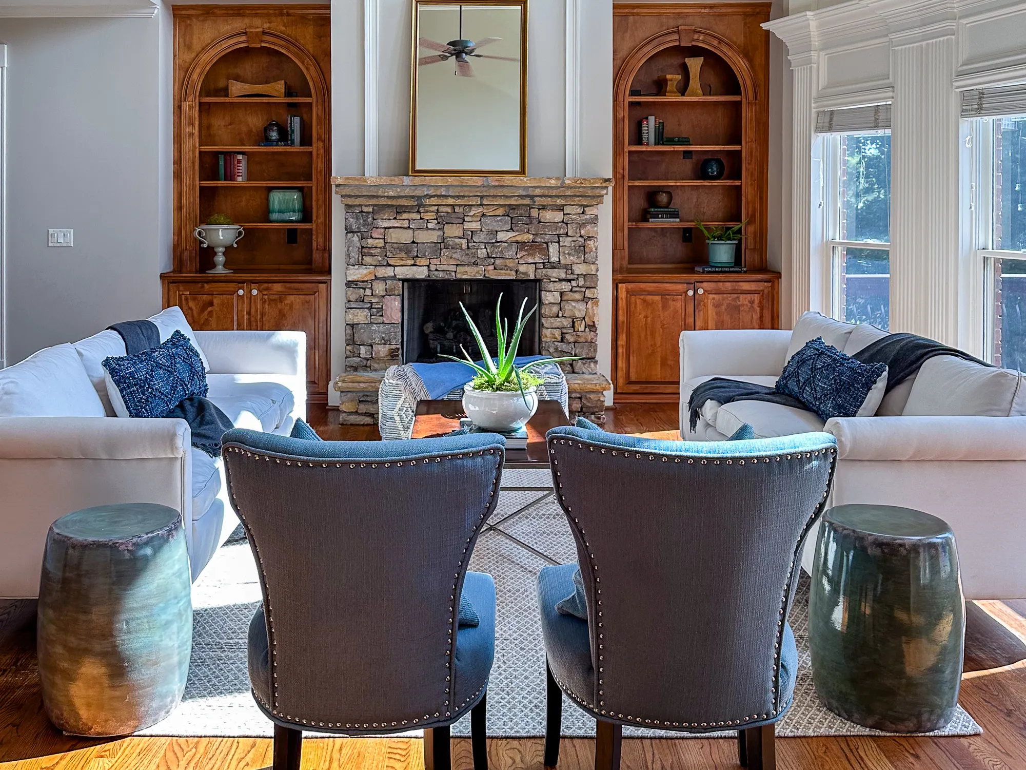 Two white sofas facing a stone fireplace between wood bookcases