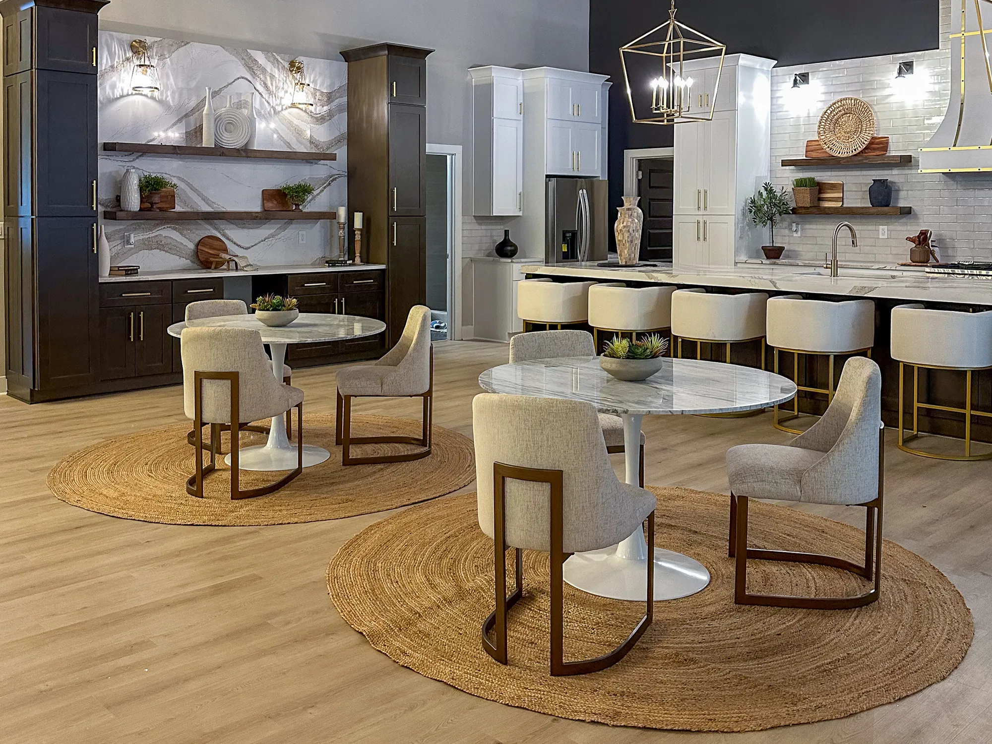 Two round dining tables on jute rugs beside a marble kitchen island