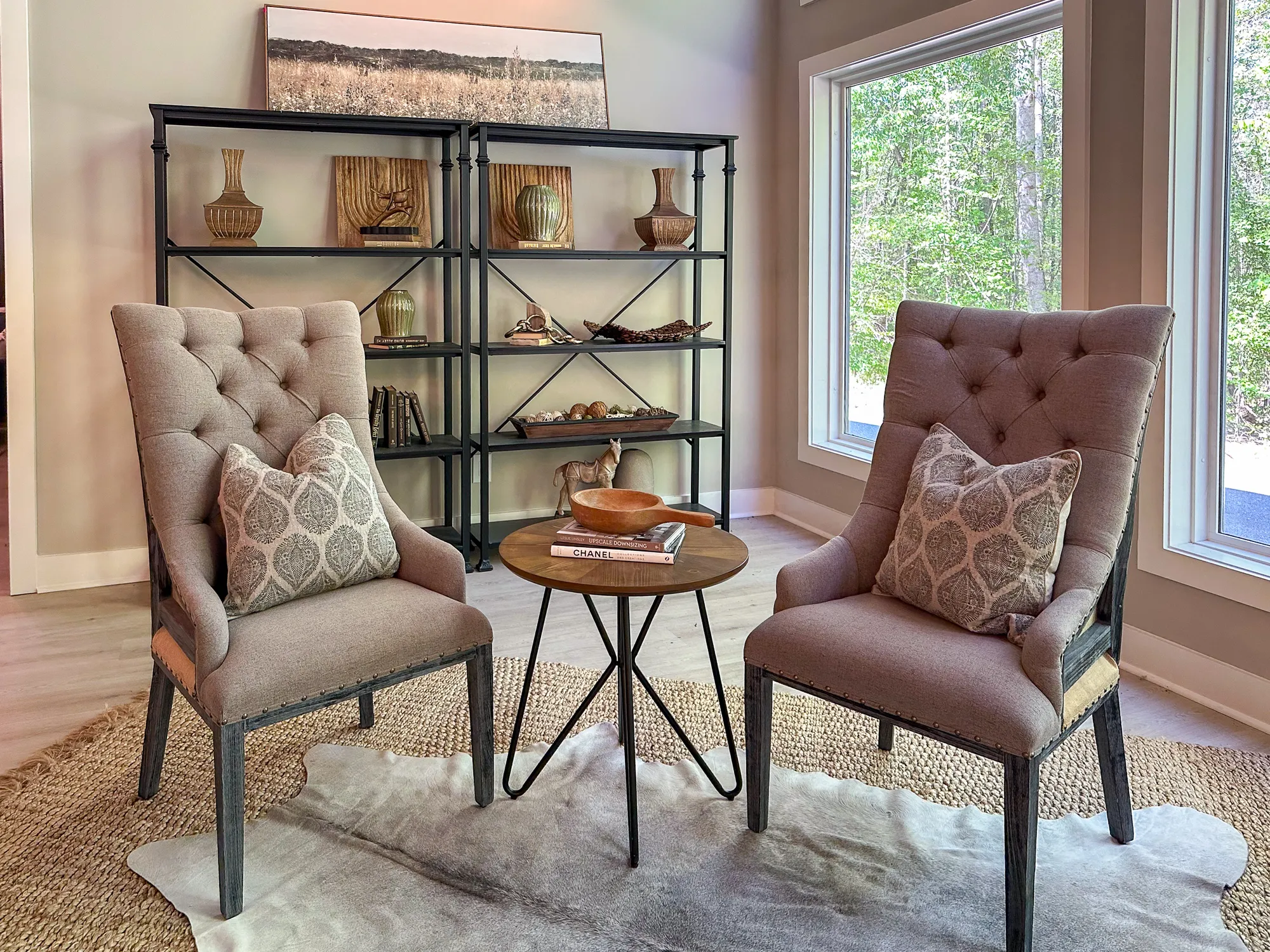 Two upholstered chairs and a wood table in front of a metal bookcase